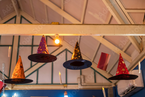 Halloween fancy witch  hats and candles hanging on ceiling inside cafe