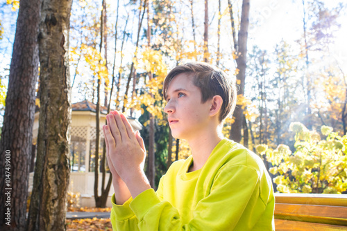 boy praying in autumn park photo