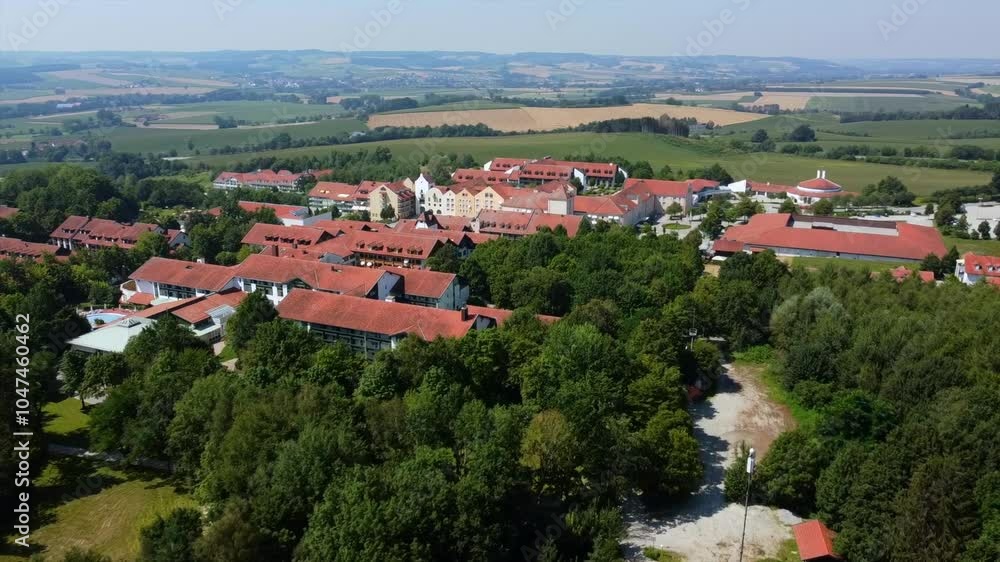 View of the Bad Griesbach spa complex with red-roofed buildings, nestled within dense forest and farmlands in Lower Bavaria. Captured on a sunny day, showcasing the serene rural landscape. View of the Bad Griesbach spa complex with red-roofed buildings, nestled within dense forest and farmlands in Lower Bavaria. Captured on a sunny day, showcasing the serene rural landscape.