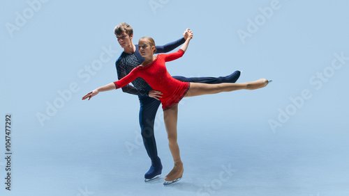 Male and female figure skating partners perform synchronized routine, showcasing their balance and athleticism against cold blue background. Concept of winter sport, elegance and grace, championship. photo