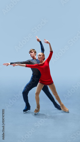 Dynamic movement. Figure skating duo captivates audience with their graceful moves on ice against cold blue background. Concept of winter sport, elegance and grace, championship. Ad photo