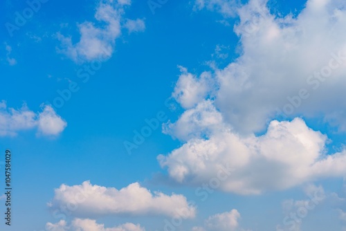 Fototapeta Naklejka Na Ścianę i Meble -  This beautiful image features a bright blue sky filled with fluffy white clouds, creating a peaceful atmosphere. Perfect for nature lovers, it invites relaxation and reflection.