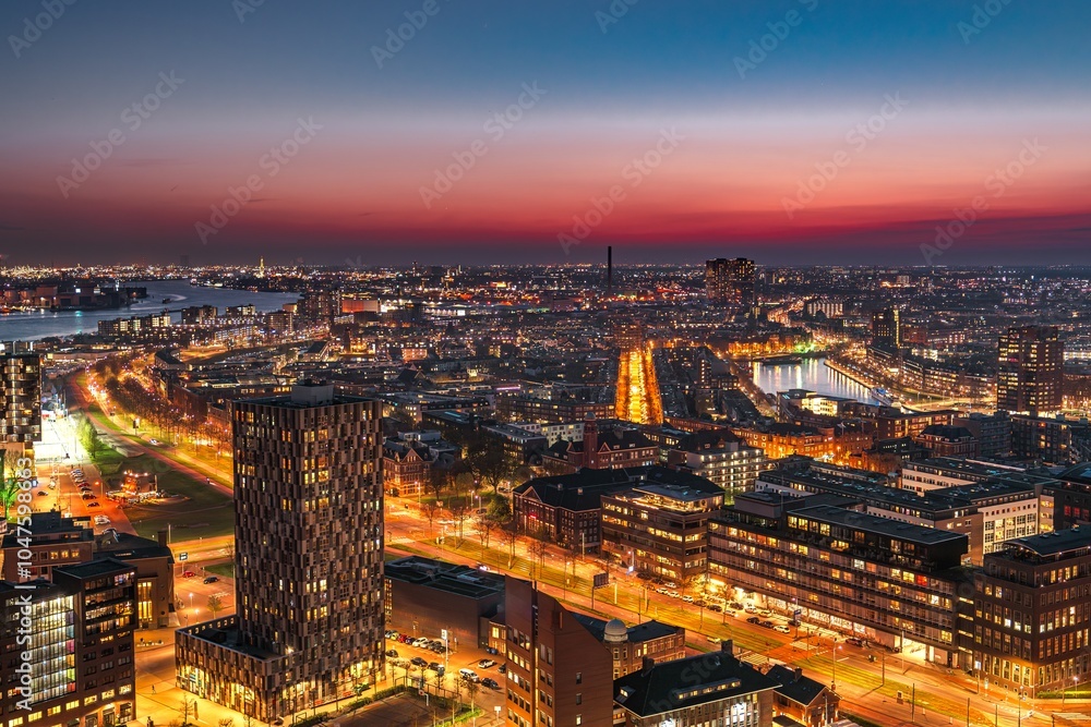 Fototapeta premium A stunning cityscape showcases modern skyscrapers along a river, illuminated by the warm glow of the setting sun, creating a vibrant and energetic atmosphere in the heart of the city.