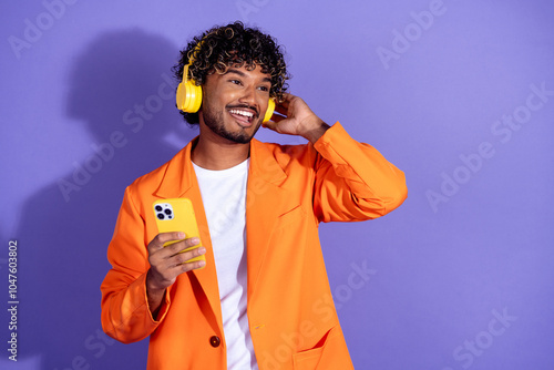 Photo of funky cool guy dressed orange jacket enjoy songs headphones modern device emtpy space isolated purple color background photo