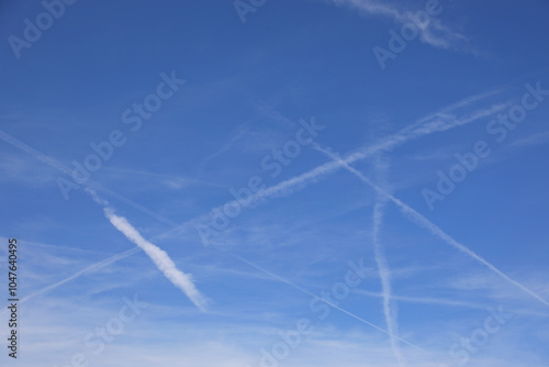 white contrails stretch across a bright blue sky creating a sharp contrast while evoking thoughts of global conspiracy