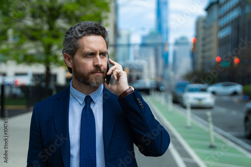 Businessman with phone outdoor. Business talk. Man walk down street talking on the phone. Serious Man in suit talking on the phone. Outdoor portrait of Businessman with smartphone.