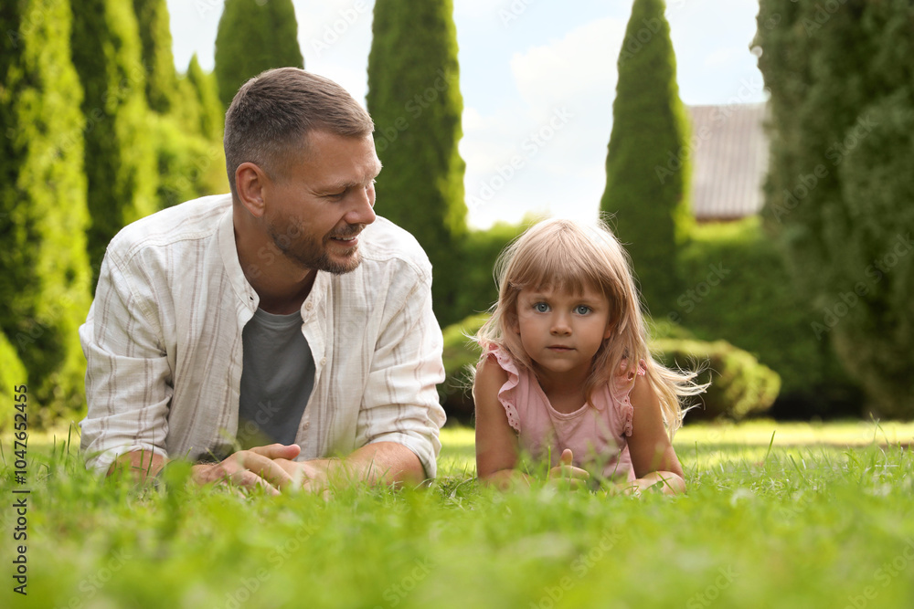 Father and his daughter spending time together on green lawn in park Father and his daughter spending time together on green lawn in park