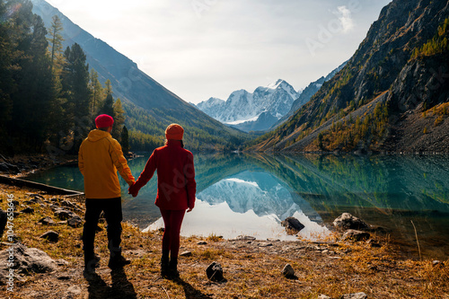 a couple of tourists in love on the shore of the mountain lake Shavlinsky in Altai in autumn photo