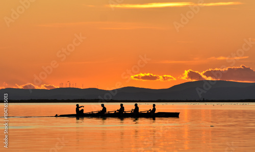 Silhouette of persons rowing on a boat at sunset	