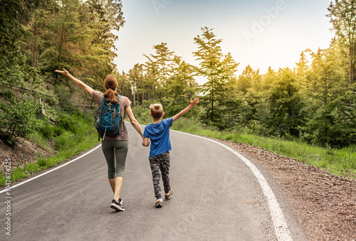 Happy family mother child enjoying time outdoors walking in the forest down country road feeling free,  travel, hiking adventure #1047674225