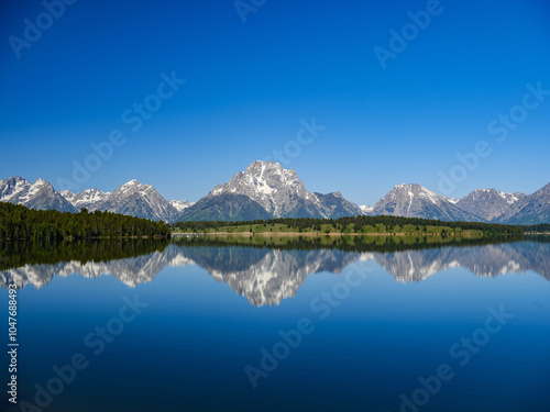 A perfect summer day reflections of snow-covered Grand Teton mountains in a mountain lake  in Wyoming photo