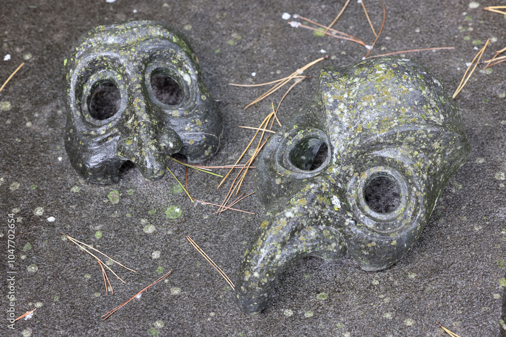 two masks on a grave stone