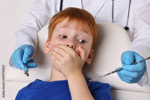 Dental phobia. Dentist working with scared little boy photo