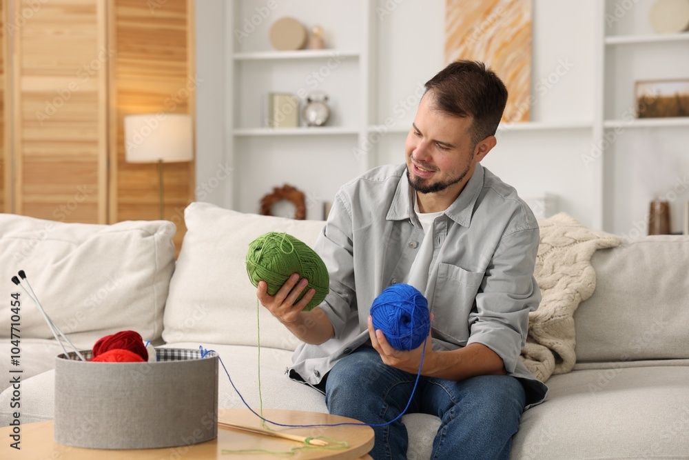 Fototapeta premium Man with colorful yarns on sofa at home. Knitting material