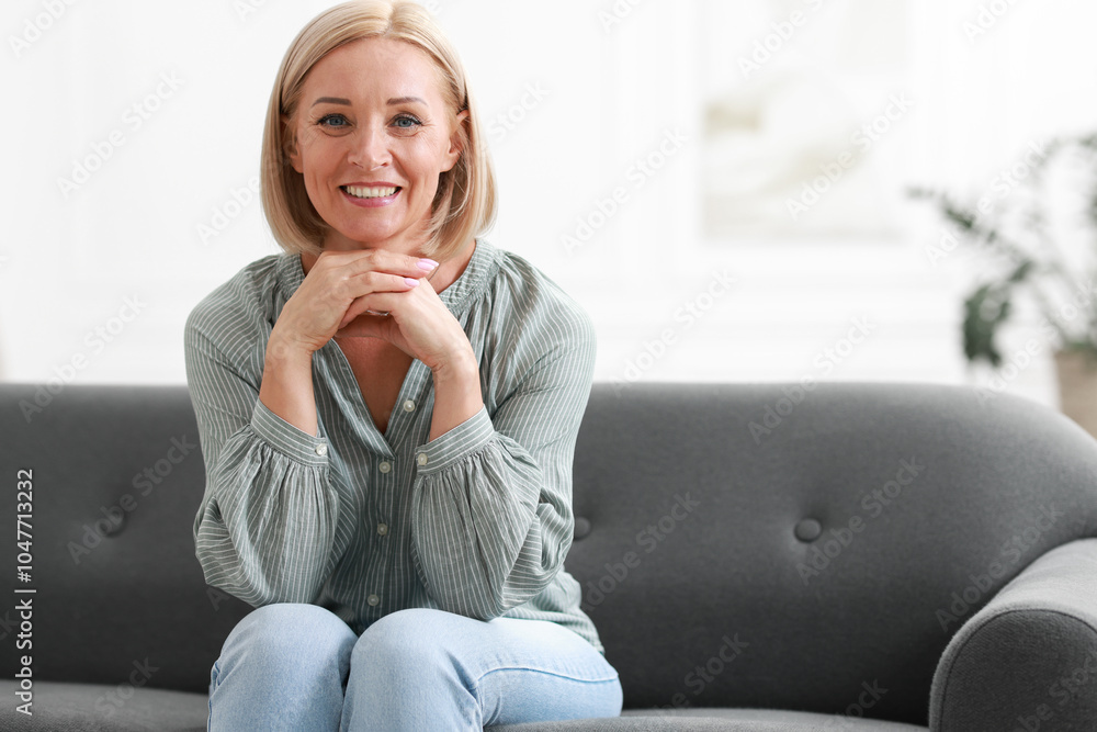 Happy middle aged woman on sofa indoors, space for text Happy middle aged woman on sofa indoors, space for text
