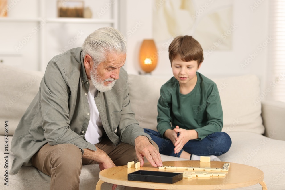 © New Africa - Grandpa and his grandson playing dominoes at table indoors