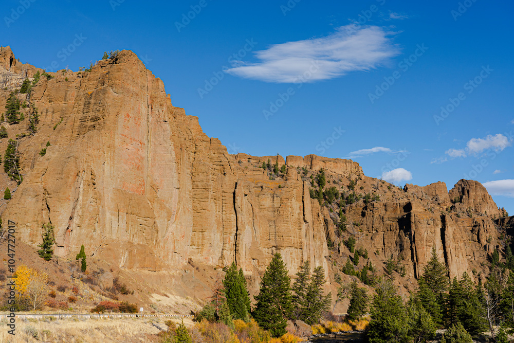 Look at the tall cliffs lining Scenic Byway 14-16-20 in Shoshone National Forest near Cody, Wyoming. Blue sky above & pine trees below make a scenic view for tourists. Look at the tall cliffs lining Scenic Byway 14-16-20 in Shoshone National Forest near Cody, Wyoming. Blue sky above & pine trees below make a scenic view for tourists.