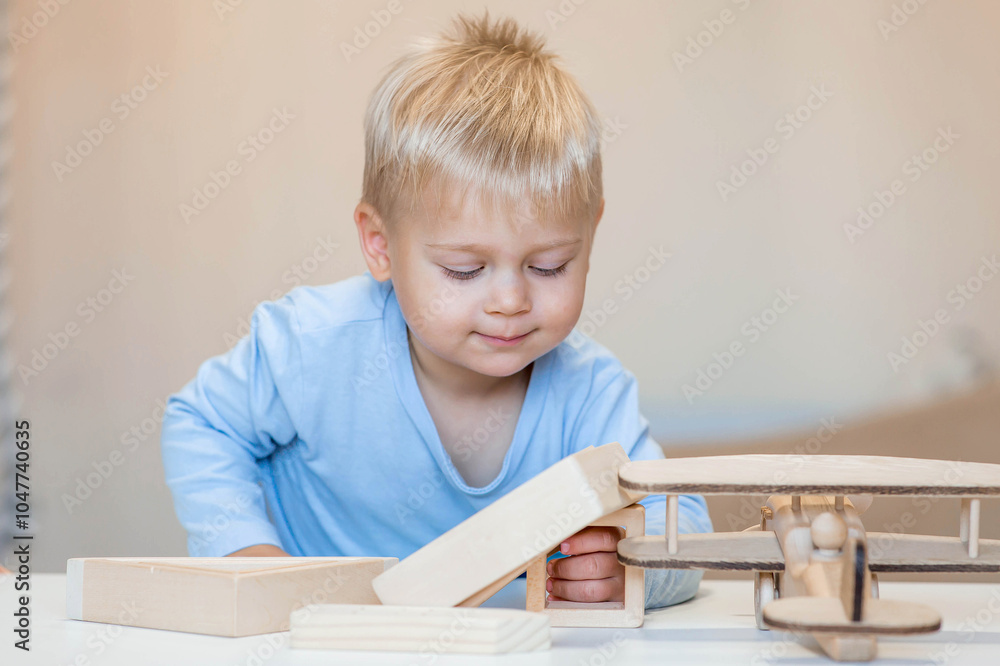 A little boy of 2 years old is playing a developing logistics constructor. Children's wooden toys. Montessori for child development. A little boy of 2 years old is playing a developing logistics constructor. Children's wooden toys. Montessori for child development.