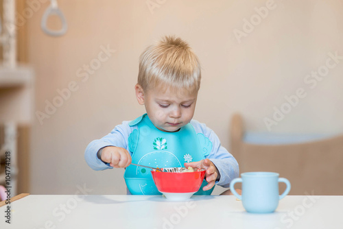 Baby food. Eating. Feeding the baby. A cute kid eats on his own with a spoon. Healthy eating. Family and children.