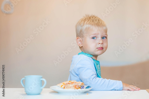 Unhealthy food for children. Eating. A cute 2-year-old kid eats pizza for lunch. Fast food. Family and children.