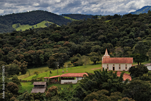 Saint Joseph of Boa Vista church  among lush green mountains, under a dramatic sky.