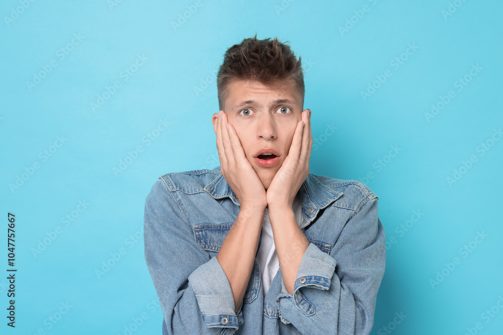 Portrait of scared young man on light blue background