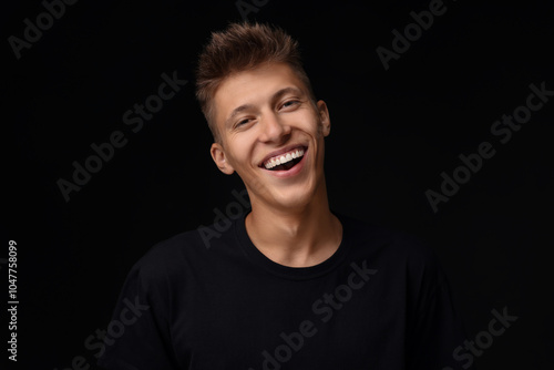 Portrait of happy young man on black background