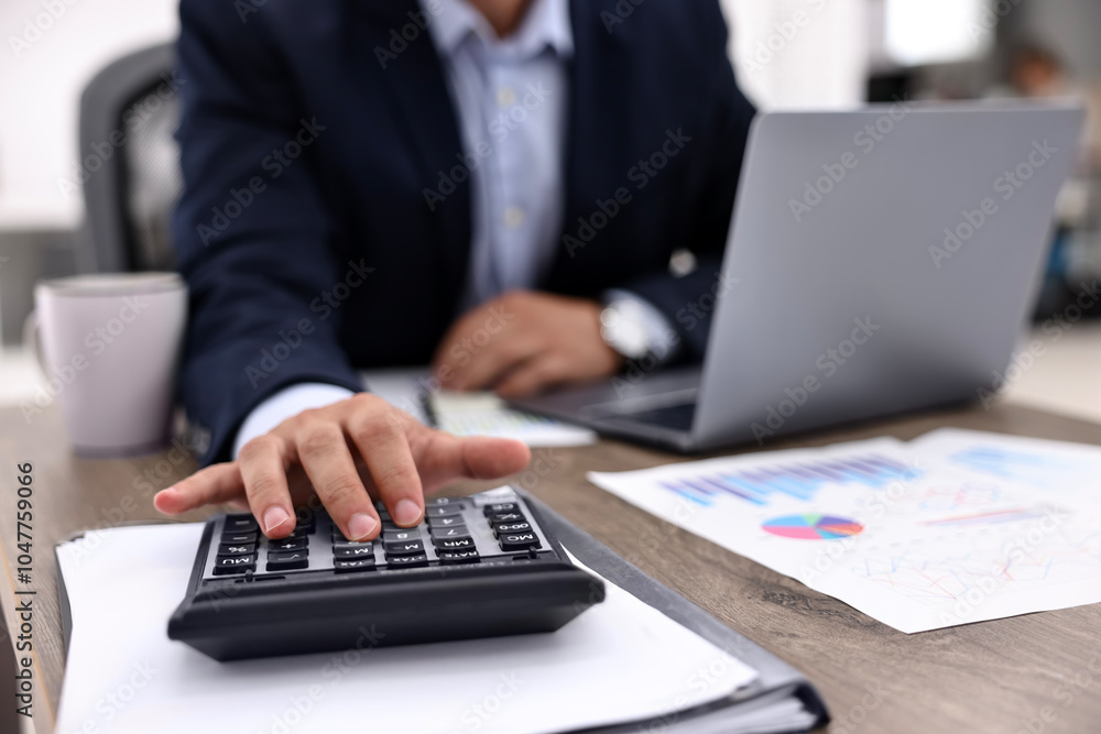 Banker using calculator at wooden table in office, closeup Banker using calculator at wooden table in office, closeup
