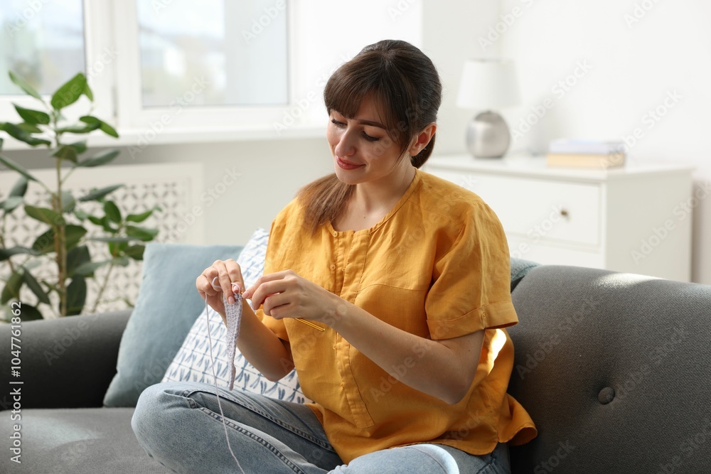 Obraz premium Beautiful woman crocheting with hook on sofa at home