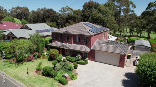 The exterior of a big house with a golf course in the background