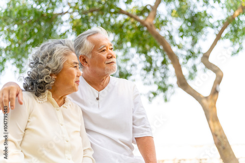 Happy Asian family senior couple enjoy outdoor lifestyle travel nature at the sea on summer beach holiday vacation. Healthy elderly husband and wife relaxing romance hug on tropical island at sunset. photo