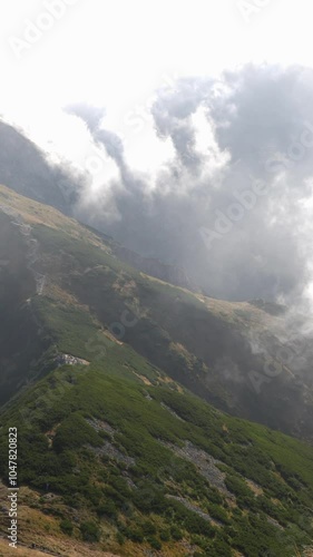 Misty mountain landscape with winding trail disappearing into the fog on calm morning. Concept of tranquil nature, adventure, and mysterious atmospheres. High quality 4k footage