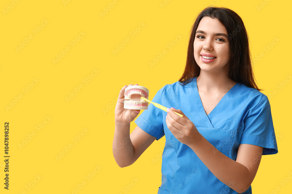 Female dentist with jaw model and toothbrush on yellow background. World Dentist Day Female dentist with jaw model and toothbrush on yellow background. World Dentist Day