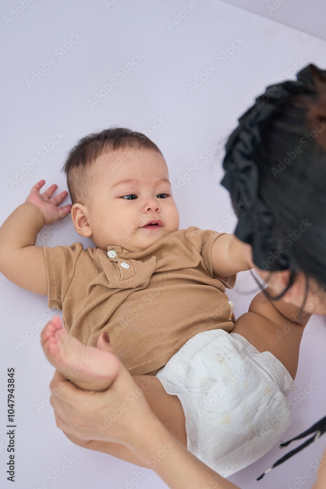 Mom is playing with her son, a boy lying on the white background Mom is playing with her son, a boy lying on the white background