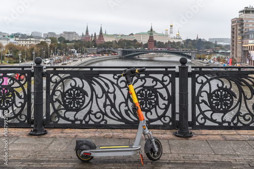 An electric scooter stands on a bridge in Moscow with a view of the Kremlin. Selective focus.
