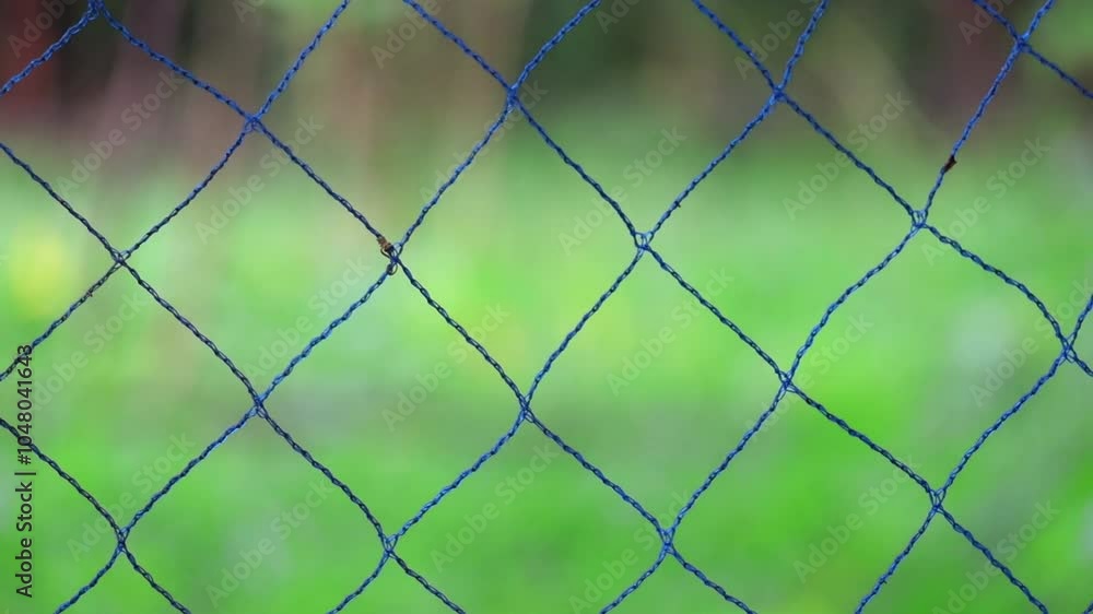 Blue thick yarn fence with blurred nature green background. Blue thick yarn fence with blurred nature green background.