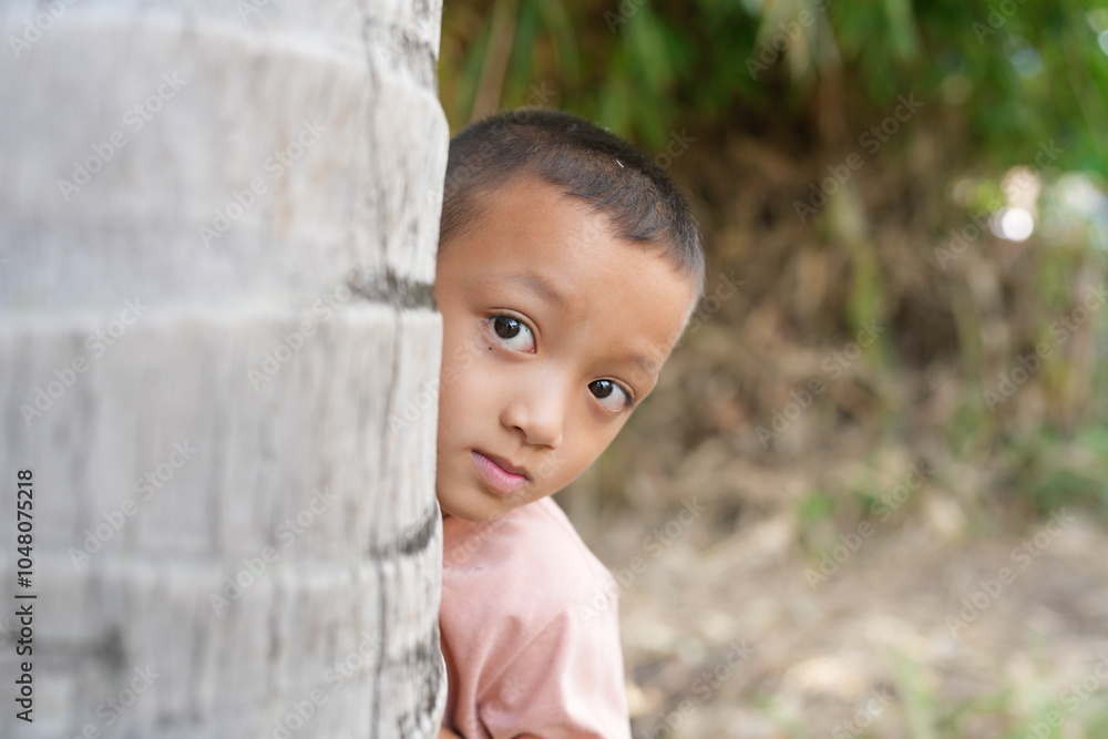 Child Hiding Behind Tree in Natural Setting Child Hiding Behind Tree in Natural Setting