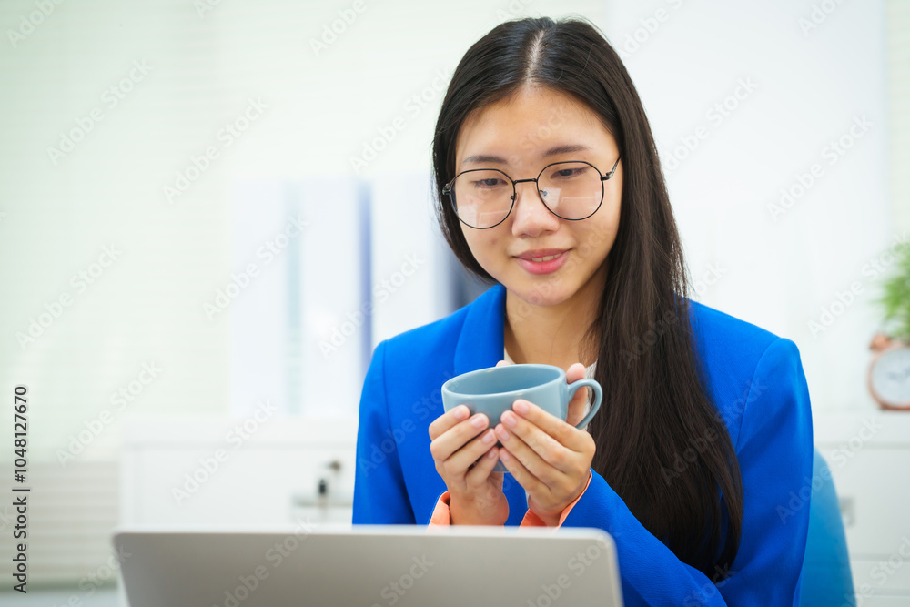 An Asian businesswoman sits at her desk in the office, discussing her work on a business plan. She emphasizes strategic planning, target group identification, and comprehensive business analysis