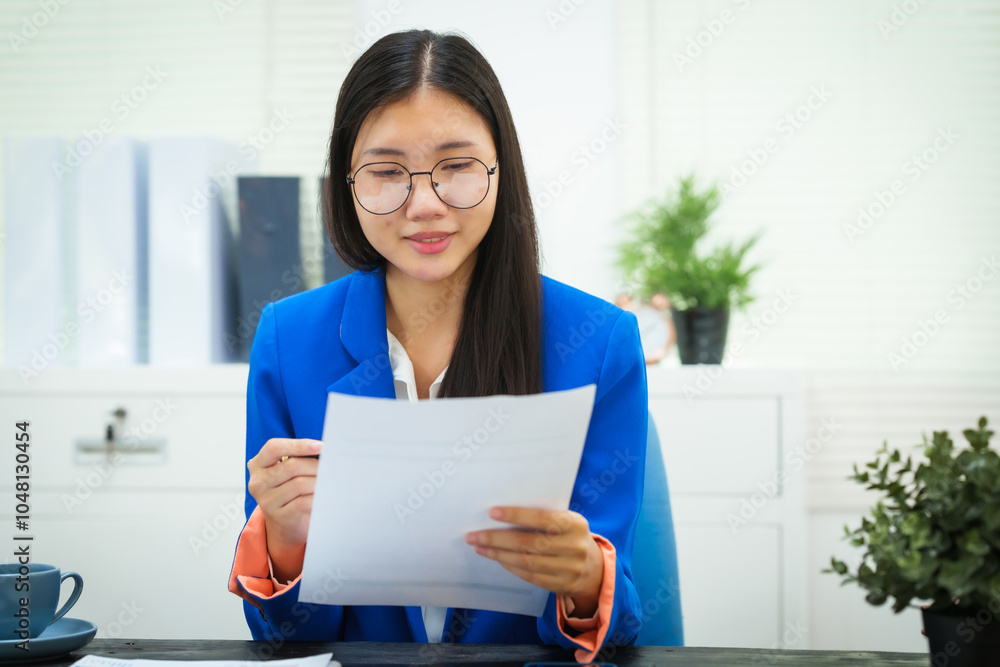 A young businesswoman works diligently at her office desk, checking documents and analyzing finances. She focuses on strategic planning to ensure the success and growth of her business A young businesswoman works diligently at her office desk, checking documents and analyzing finances. She focuses on strategic planning to ensure the success and growth of her business