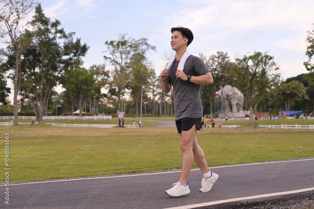 Happy smiling man jogging through a park during the late afternoon Happy smiling man jogging through a park during the late afternoon