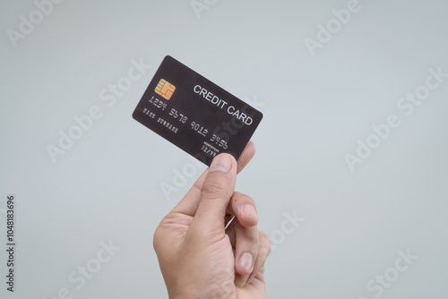 A close-up of a man’s hand holding a bank credit card against a white background, emphasizing secure online payment services and financial convenience for shopping and banking transactions