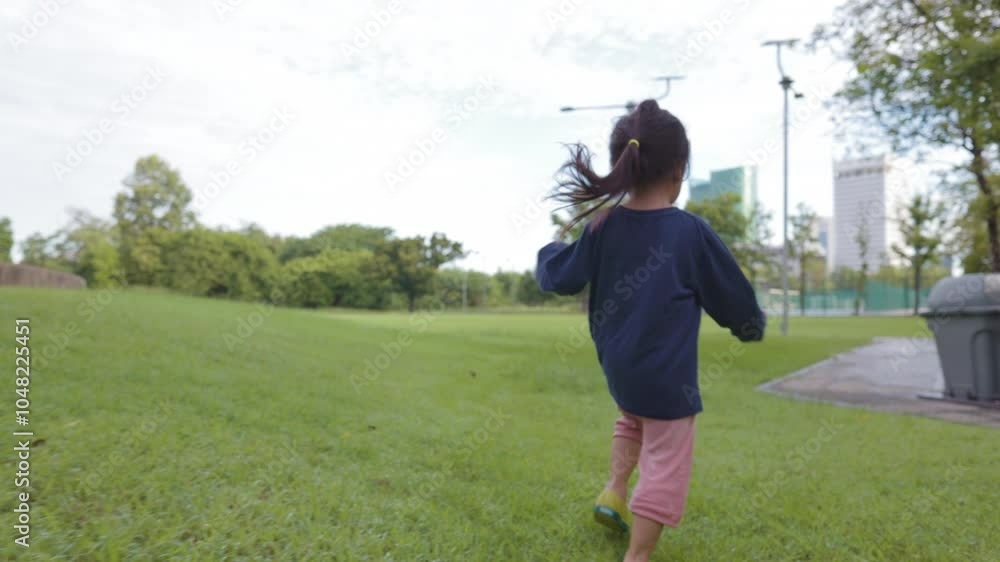 Adorable little 3 -4 year asian preschool girl enjoying run on green meadow city paublic park Adorable little 3 -4 year asian preschool girl enjoying run on green meadow city paublic park