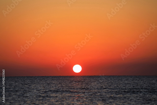 空をオレンジ色に染めて海に沈む太陽 photo