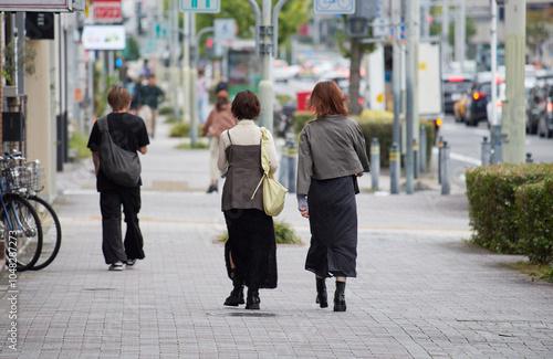 秋の昼の繁華街で歩く若い女性たちと人々の姿 photo