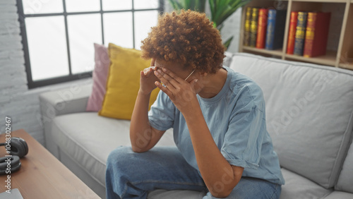 Photography A distressed african american woman sitting on a sofa indoors covering her face