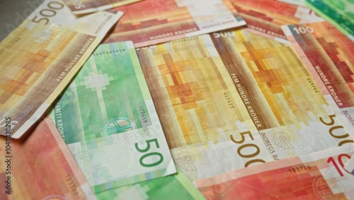 Norwegian banknotes in denominations of 50, 100, and 500 kroner spread out in a colorful and scattered arrangement. photo