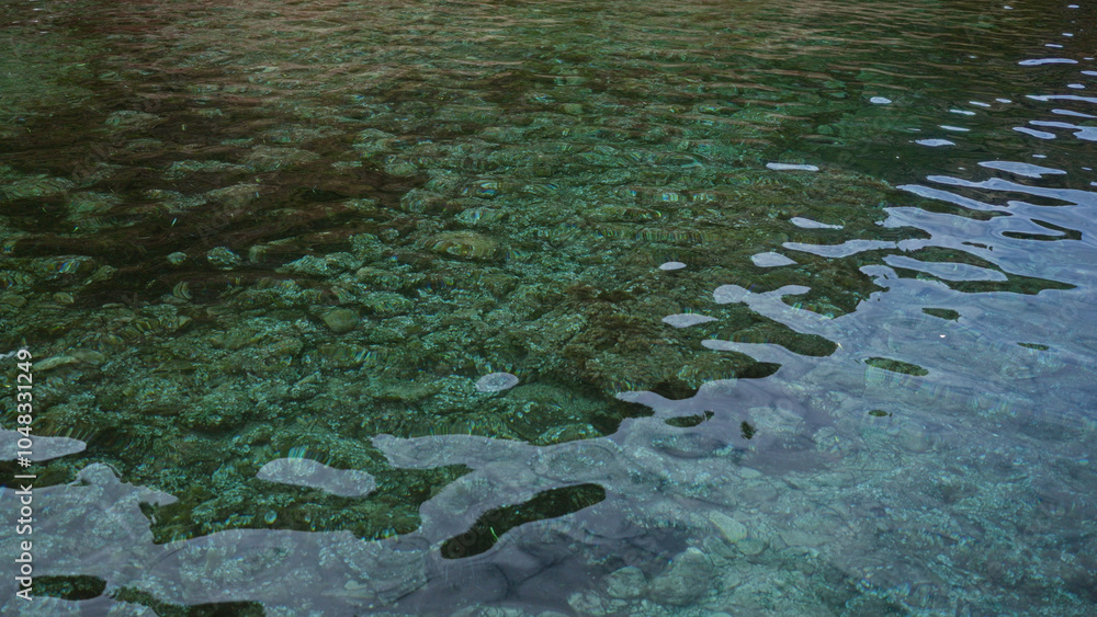 Crystal clear river water with visible rocks below the surface showcasing a serene nature scene Crystal clear river water with visible rocks below the surface showcasing a serene nature scene