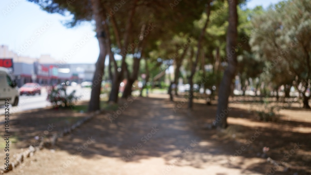 Blurred outdoor park scene with defocused trees and background, showcasing a natural setting with bokeh effect and urban elements, such as cars on the street in the distance. Blurred outdoor park scene with defocused trees and background, showcasing a natural setting with bokeh effect and urban elements, such as cars on the street in the distance.