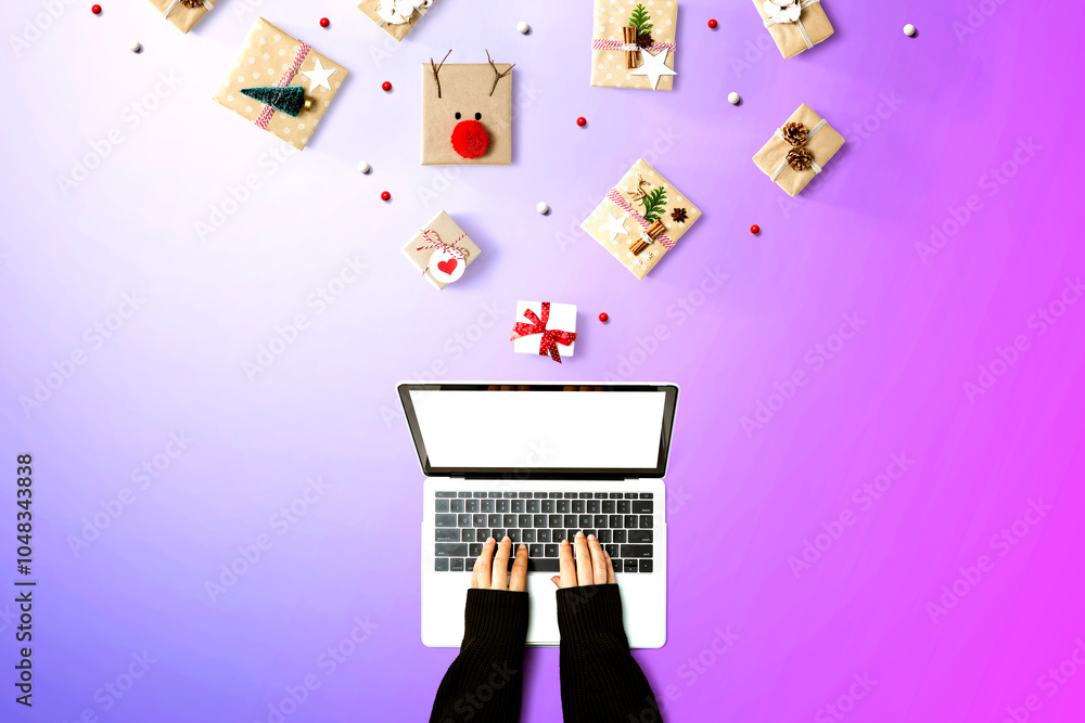 Person using a laptop computer with Christmas gift boxes from above Person using a laptop computer with Christmas gift boxes from above