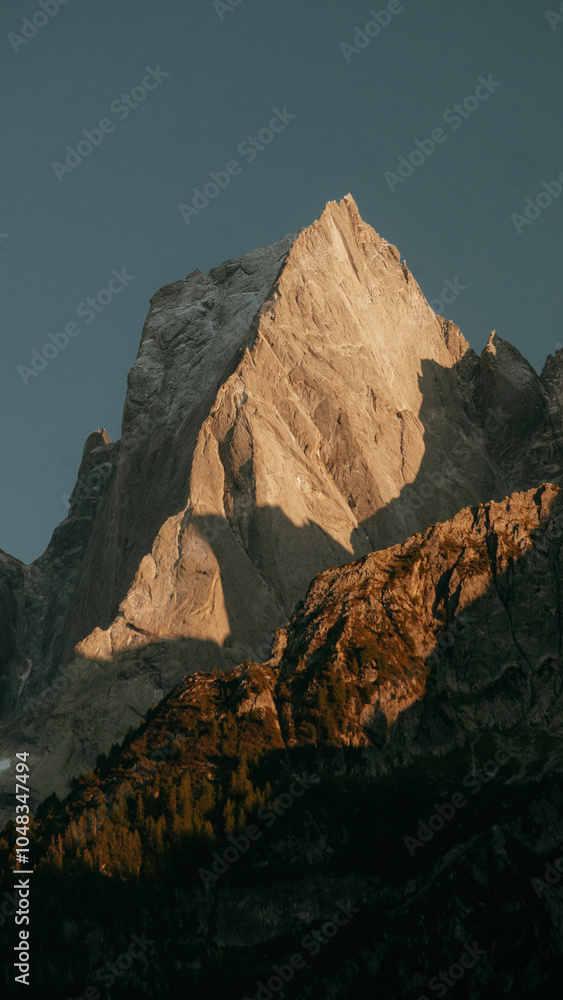 Piz Badile mountain peak in the Swiss Alps in golden evening light at sunset, Val Bregaglia, province of Sondrio, Switzerland